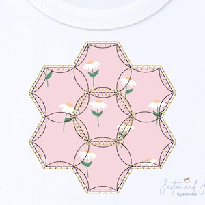 May include: A white onesie featuring a floral design. The design is composed of six connected hexagonal shapes, each filled with a pink background and white daisies. The edges are outlined with gold and navy stitching. The text "Jaxton and Jill by ElleHess" is in the bottom right corner.