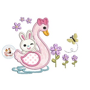 Pode incluir: Um cisne rosa com um coelho branco sentado em cima, rodeado de flores roxas e uma borboleta amarela. O cisne tem bolinhas rosa e um laço rosa.