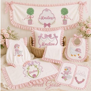 May include: A collection of white fabric items with pink gingham ruffles, including a valance, a pillow, a romper, a bib, and burp cloths. The items feature embroidered designs of geese wearing bonnets, topiary trees, and the name Hailey.