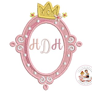 May include: Pink embroidered oval frame with a gold crown and floral accents. The frame features the initials "H D H" in a delicate script. The design includes decorative swirls and pearl-like embellishments, perfect for embroidery projects.
