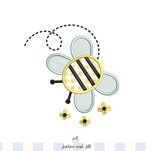 May include: An embroidered bee design with a yellow and black checkered body, black stripes, and light blue wings. The bee has black antennae and is surrounded by three small yellow flowers. A dotted line trails from the bee.