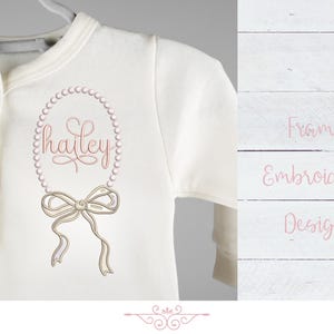 May include: A white baby onesie with a pink pearl frame embroidery design featuring the name "hailey" and a bow.