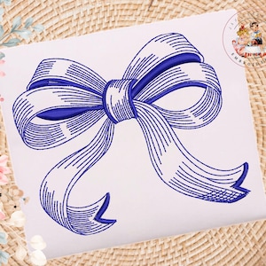May include: A blue and white embroidered bow design. The bow is intricately detailed with a striped pattern, creating a textured appearance. The design is centered on a white background, with a woven texture visible in the background.