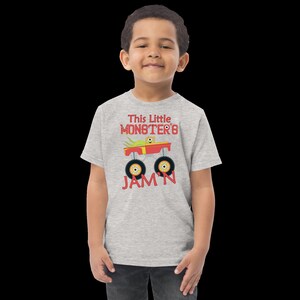 May include: A grey short-sleeved t-shirt with a red monster truck graphic and the text "This Little Monster's Jam'n".