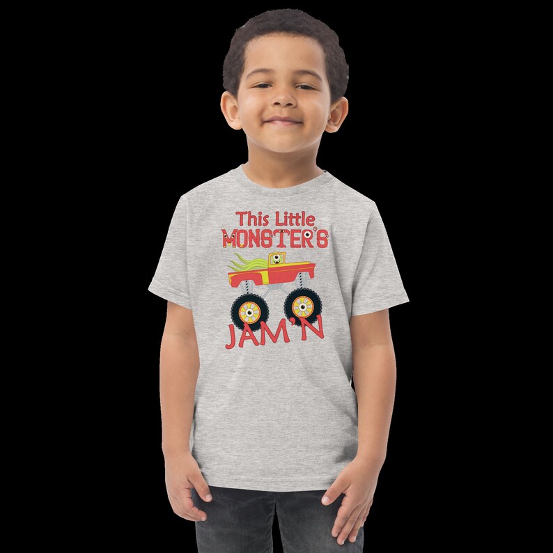 May include: A grey short-sleeved t-shirt with a red monster truck graphic and the text "This Little Monster's Jam'n".