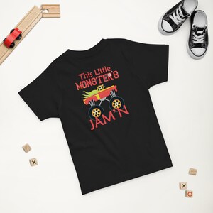 May include: Black short-sleeved t-shirt with a red monster truck graphic and the text "This Little Monster's Jam'n".