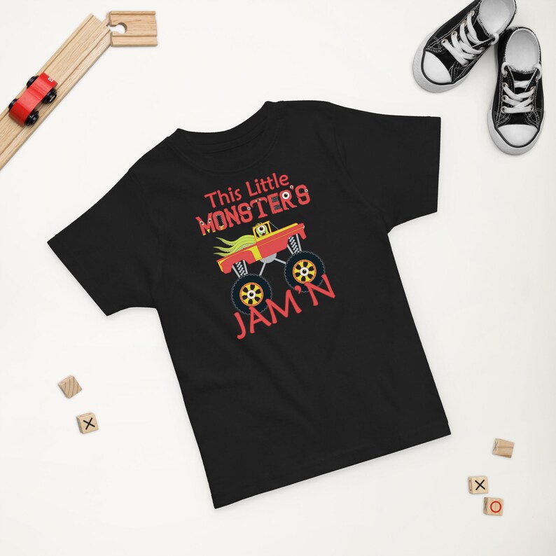 May include: Black short-sleeved t-shirt with a red monster truck graphic and the text "This Little Monster's Jam'n".