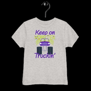 May include: Gray t-shirt with a purple and green monster truck graphic. The truck has a single eye and the text "Keep on Monster Truckin'" is printed on the shirt.