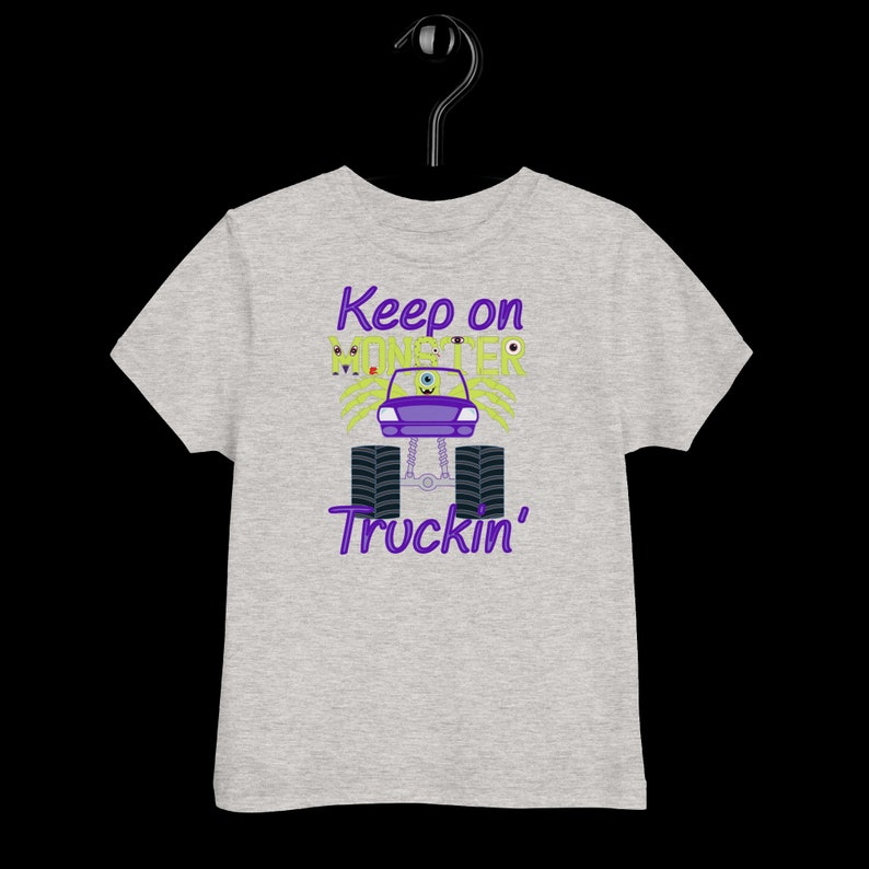 May include: Gray t-shirt with a purple and green monster truck graphic. The truck has a single eye and the text "Keep on Monster Truckin'" is printed on the shirt.