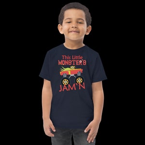 May include: A navy blue t-shirt with a red monster truck graphic and the text "This Little Monster's Jam'n".