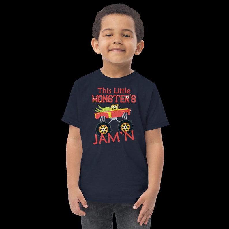 May include: A navy blue t-shirt with a red monster truck graphic and the text "This Little Monster's Jam'n".