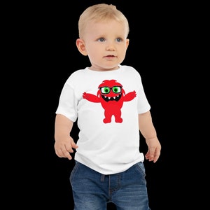May include: A white toddler t-shirt with a red monster wearing glasses graphic. The monster has green eyes and a big smile.