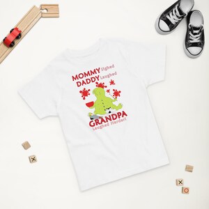 Puede incluir: Camiseta blanca con una ilustraci&oacute;n de un monstruo verde y el texto "Mommy sighed, Daddy laughed, Grandpa laughed harder!"