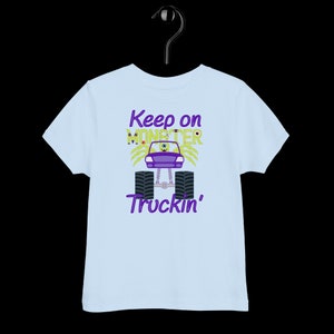 May include: Light blue toddler t-shirt with a purple monster truck graphic and the text "Keep on Monster Truckin'" in purple.