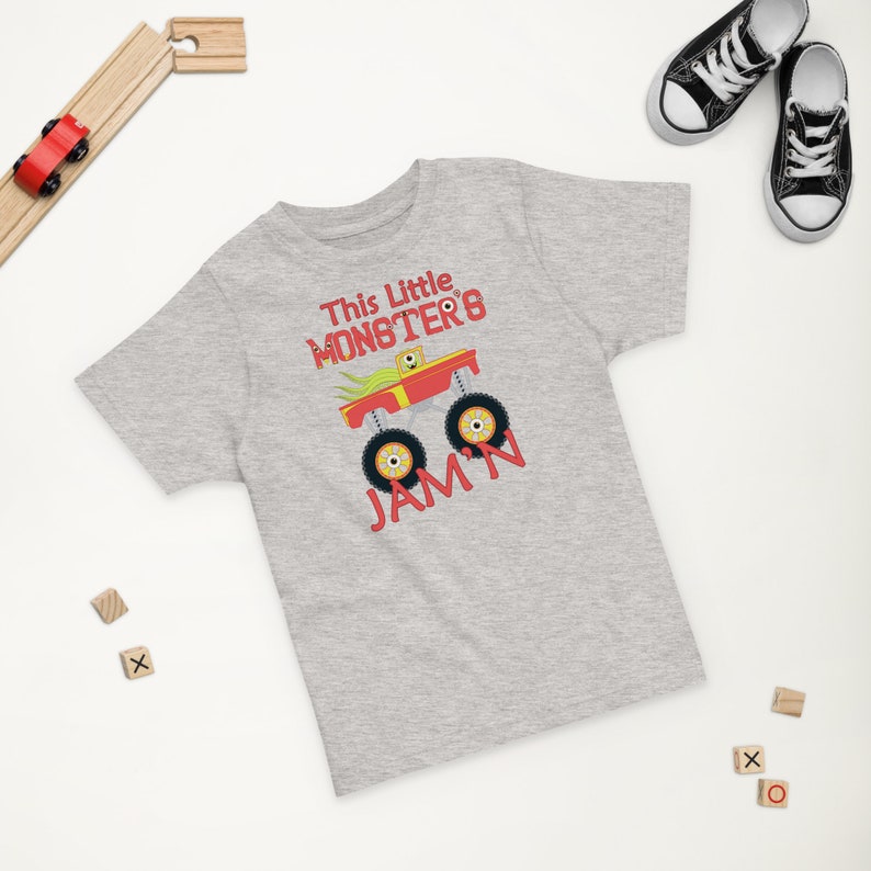 May include: A grey short-sleeved t-shirt with a red monster truck graphic and the text "This Little Monster's Jam'n".