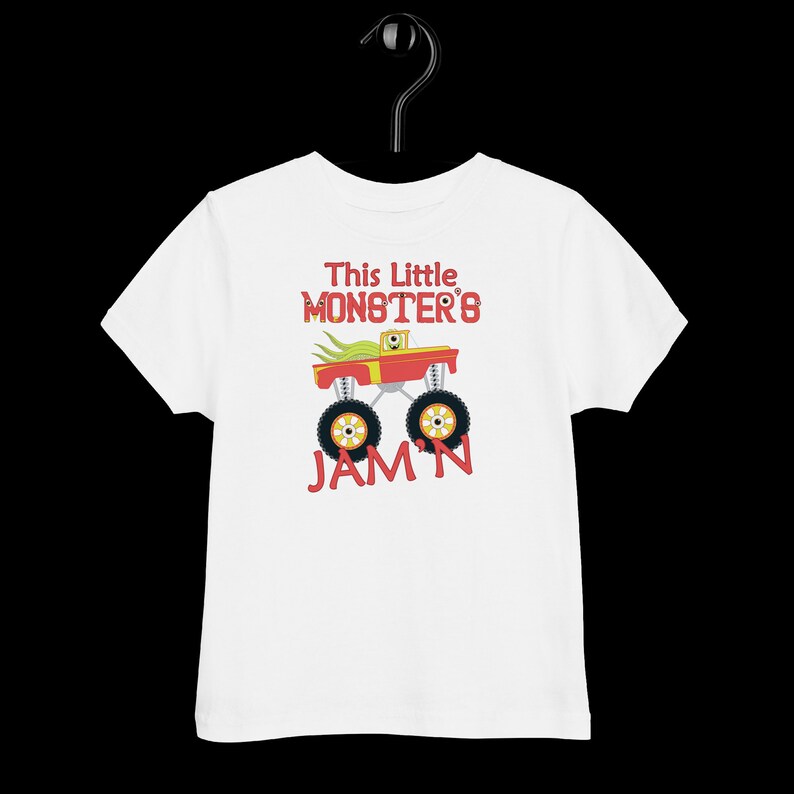 May include: White toddler t-shirt featuring a red monster truck graphic and the text "This Little Monster's Jam'n".