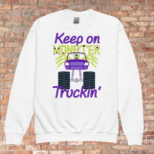 May include: White sweatshirt with a green monster truck graphic and the text "Keep on Monster Truckin'" in purple.