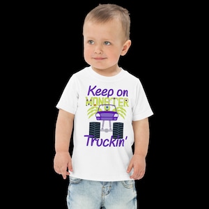 May include: White toddler t-shirt with a purple and green monster truck graphic. The text "Keep on Monster Truckin'" is printed on the shirt.
