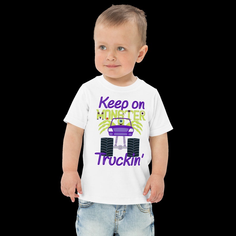 May include: White toddler t-shirt with a purple and green monster truck graphic. The text "Keep on Monster Truckin'" is printed on the shirt.