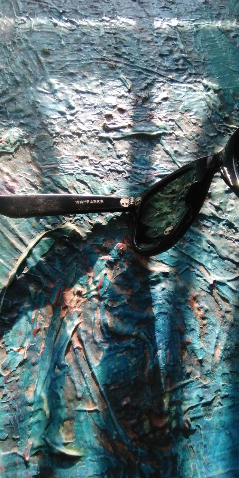 K&ouml;nnte beinhalten: Schwarze Sonnenbrille mit gl&auml;nzendem Finish und dem Wort WAYFARER in wei&szlig;em Aufdruck auf dem inneren B&uuml;gel. Der Rahmen hat eine klassische Form mit einem sichtbaren Metallscharnier am B&uuml;gelansatz und dunkel get&ouml;nten Gl&auml;sern.