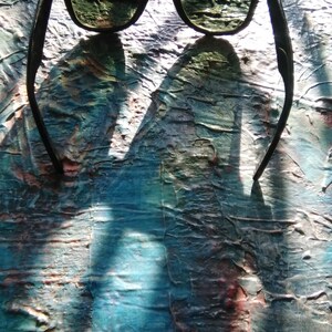 K&ouml;nnte beinhalten: Sonnenbrille mit schwarzem Rahmen und dunkelgr&uuml;n get&ouml;nten Gl&auml;sern. Das Gestell hat eine klassische rechteckige Form mit abgerundeten Kanten und kleinen metallischen Akzenten an den oberen Ecken der Vorderseite.