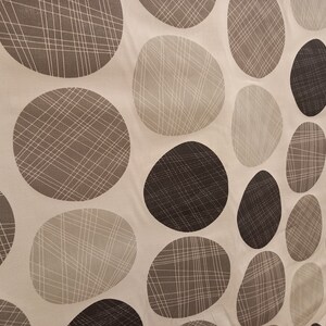 May include: Beige fabric with a repeating pattern of brown and beige circles. The circles have a criss-cross pattern.