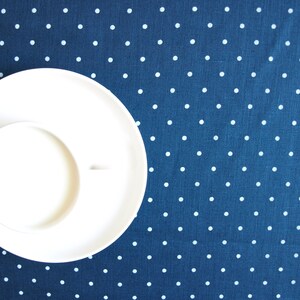 May include: A white saucer and cup on a blue background with white polka dots.