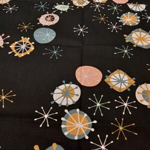 Pode incluir: Tecido preto com um padrão repetido de estrelas e círculos estilizados brancos, rosa, azuis e dourados.