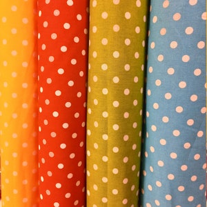 Puede incluir: Cuatro rollos de tela con lunares blancos sobre un fondo naranja, rojo, verde y azul.