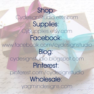 May include: A gift box wrapped in beige paper, adorned with a purple ribbon and a light blue ribbon. The image includes text with shop and social media information, including Etsy and Facebook URLs.