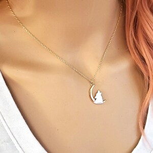 May include: A gold chain necklace with a pendant featuring a wolf howling at the moon.