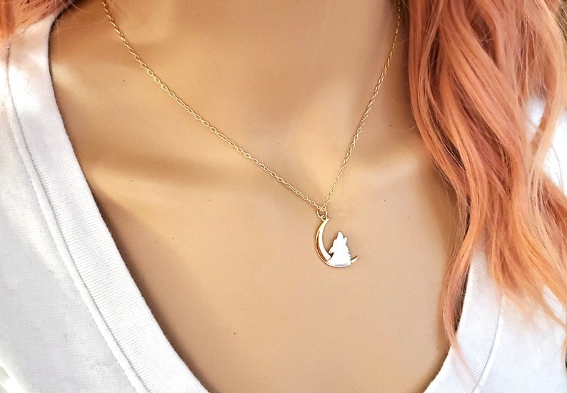 May include: A gold chain necklace with a pendant featuring a wolf howling at the moon.
