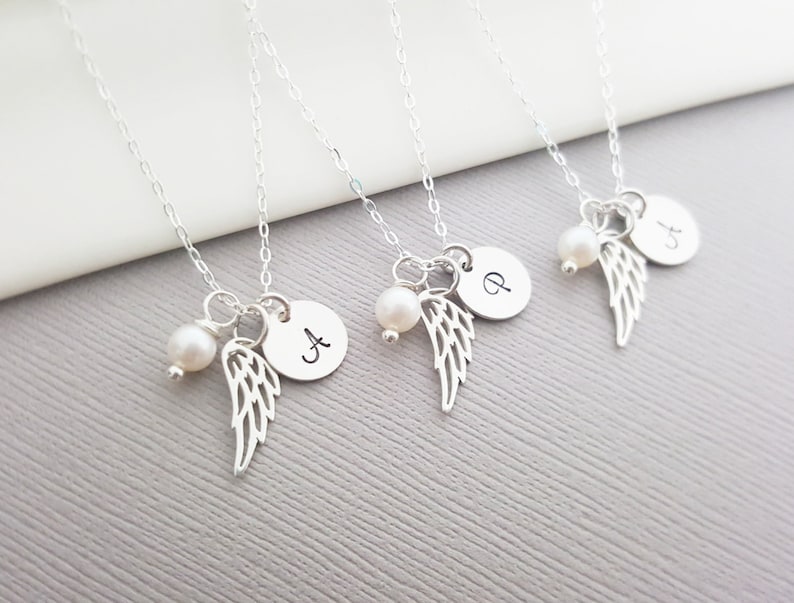Puede incluir: Cuatro collares de plata con un dije de perla y ala de &aacute;ngel. Cada collar tiene un peque&ntilde;o disco de plata con una letra: A, P y J.