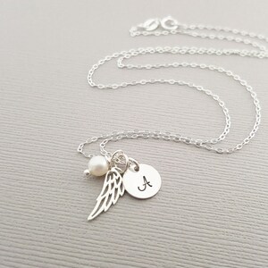 Puede incluir: Un collar de plata con un peque&ntilde;o dije de perla, un dije de ala de &aacute;ngel de plata y un dije de disco de plata con la letra 'A' grabada.