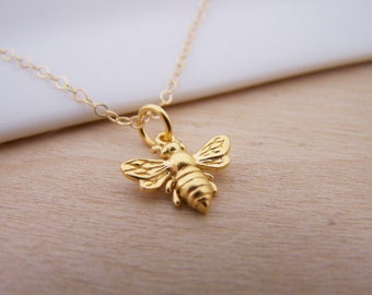 May include: A gold bee charm necklace with a delicate chain. The bee charm is detailed with wings and a body.