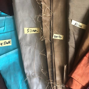 May include: Five fabric swatches labeled with their colors: Sea Shell, Silver, Gold, Olive, and a fourth color that is not labeled. The swatches are arranged vertically, with the Sea Shell swatch at the bottom and the Olive swatch at the top.