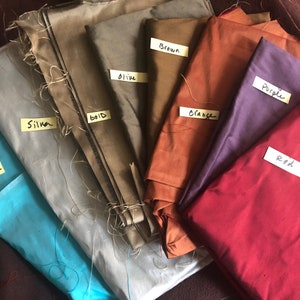 May include: A collection of fabric swatches in various colors, including egg shell, silk, gold, olive, brown, orange, purple, and red. Each swatch is labeled with its corresponding color.