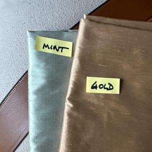 May include: Two fabric swatches, one mint green and one gold, with handwritten labels "MINT" and "GOLD" on them.