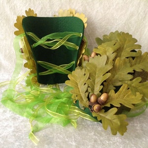 May include: A green felt hat with a green ribbon and oak leaves and acorns. The hat is decorated with gold leaves.