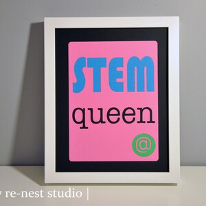 May include: A framed print with a pink background and black text that reads "STEM queen @". The text "STEM" is in blue.