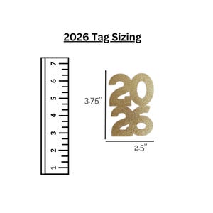 May include: Gold glitter paper tag cut-out in the shape of the year 2026. The tag is 3.75 inches tall and 2.5 inches wide. The text "2026 Tag Sizing" is above the tag. A ruler is to the left of the tag.
