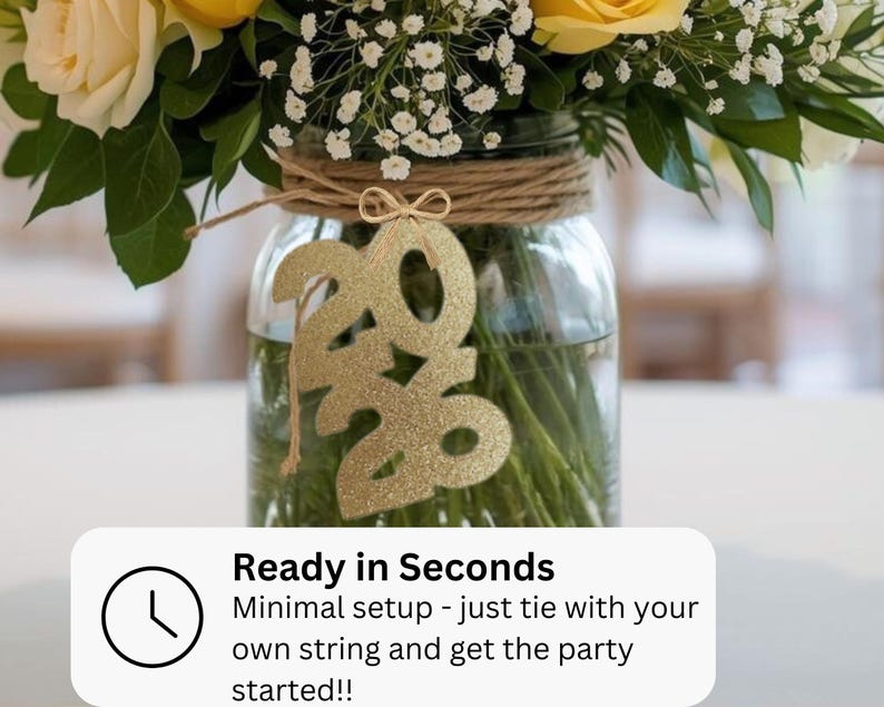 May include: A clear glass jar with a floral arrangement, featuring yellow roses and white baby's breath. A gold glitter "2020" ornament hangs in front. The jar is wrapped with twine. Text on the bottom reads "Ready in Seconds" and "Minimal setup - just tie with your own string and get the party started!!"