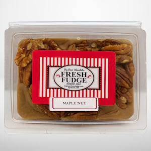 May include: A clear plastic container with a square of maple nut fudge topped with pecan pieces. The fudge is labeled "Big Bear Chocolates Fresh Fudge (509) 891-2662 bigbearchocolates.com Spokane, WA Maple Nut"