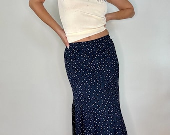 May include: A cream-colored tank top with a floral design and a navy blue skirt with white polka dots. The skirt has a flared hem. The outfit is suitable for casual wear.
