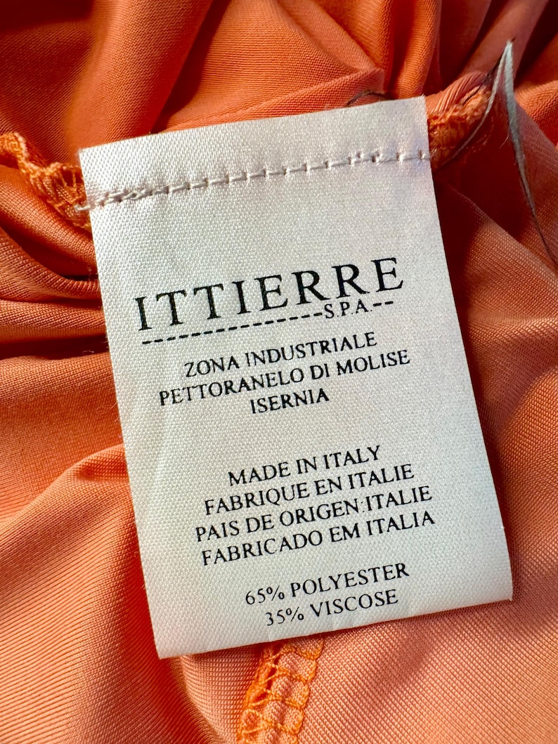 Może przedstawiać: Biała metka odzieżowa z czarnym tekstem, kt&oacute;ry brzmi "ITTIERRE S.P.A. ZONA INDUSTRIALE PETTORANELO DI MOLISE ISERNIA MADE IN ITALY FABRIQUE EN ITALIE PAIS DE ORIGEN ITALIE FABRICADO EM ITALIA 65% POLYESTER 35% VISCOSE".