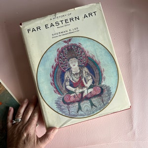 May include: A book titled "A History of Far Eastern Art" by Sherman E. Lee, Director of The Cleveland Museum of Art. The cover features a colorful illustration of a seated figure with a halo and a lotus flower.