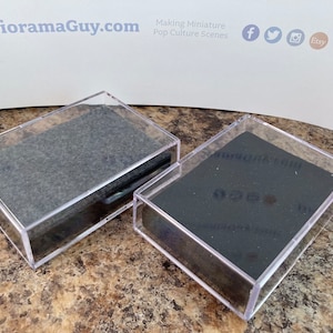May include: Two clear plastic display cases with black felt lining. The cases are empty and ready to display small items.
