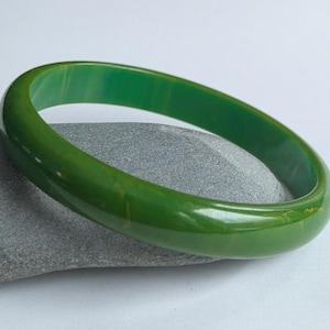 Puede incluir: Un brazalete de plástico verde. El brazalete es liso y brillante.
