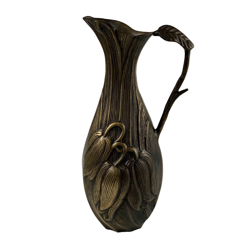 Pu&ograve; includere: Un'anfora di bronzo con un design floreale. L'anfora ha un'ampia apertura e un manico curvo. Il design floreale &egrave; in rilievo sull'anfora e presenta un gruppo di fiori stilizzati.
