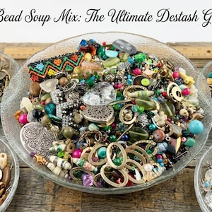 May include: A large glass bowl filled with a 1 LB bead soup mix, surrounded by four smaller bowls containing assorted beads and charms. Text reads: 1 LB Bead Soup Mix: The Ultimate Destash Grab Bag, Vintage to Modern, Upcycled to Glass, Artisan Mix.